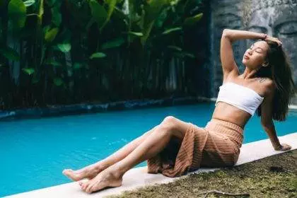 Young ethnic woman relaxing near pool in Bali