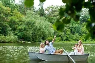 happy young family spending time together in boat on lake at park