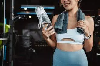 Woman drinking water recovery health exercise workout in gym fitness breaking relax