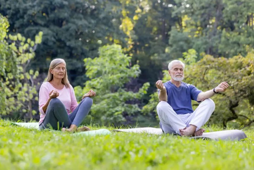 Senior couple in serene meditation pose outdoors practicing mindfulness together