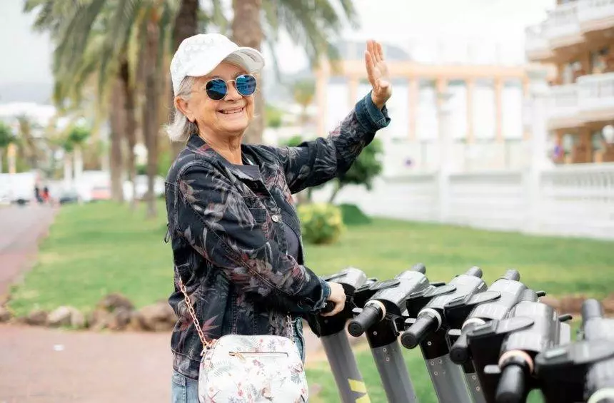 Elderly white-haired woman ready to rent electric scooter for a city tour, sustainable mobility