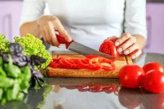 The hostess slicers vegetables in the kitchen. Making vegetarian